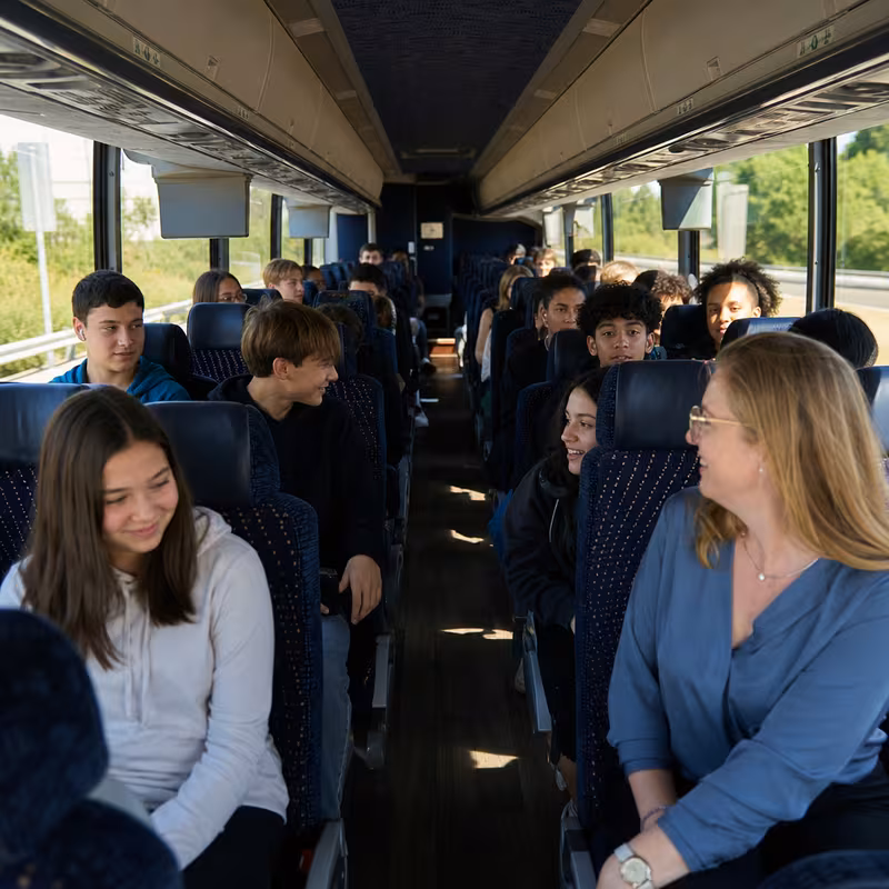 Group boarding a white charter bus for School Transportation transportation in Birmingham