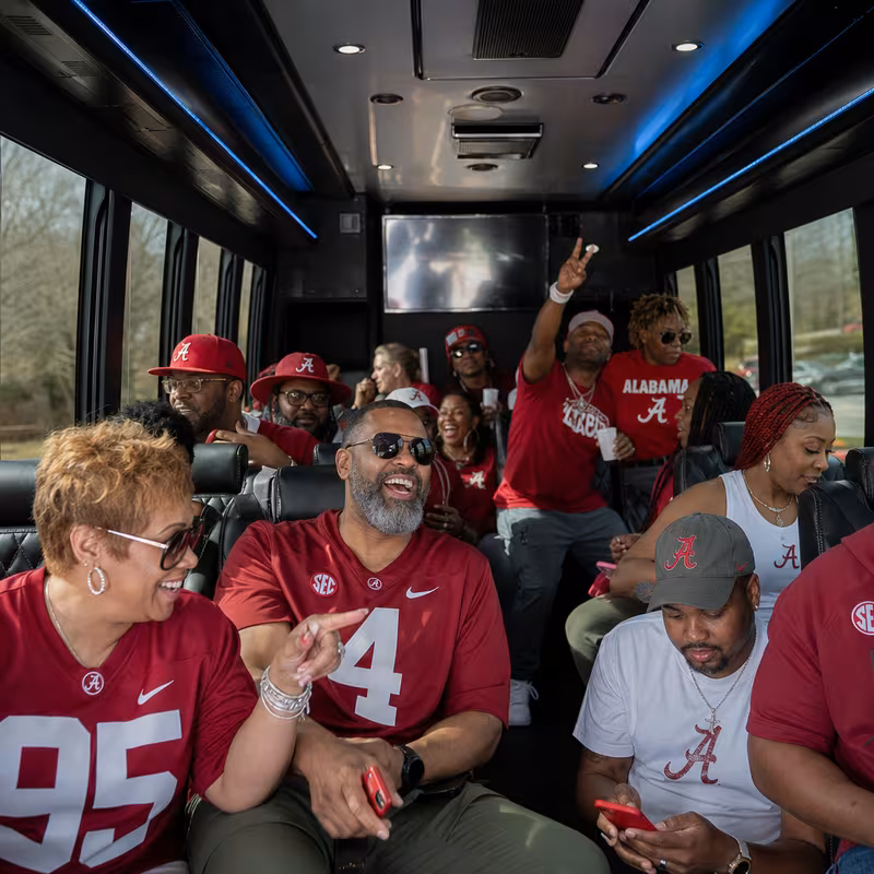 Group boarding a white charter bus for Sporting Event Transportation transportation in Birmingham